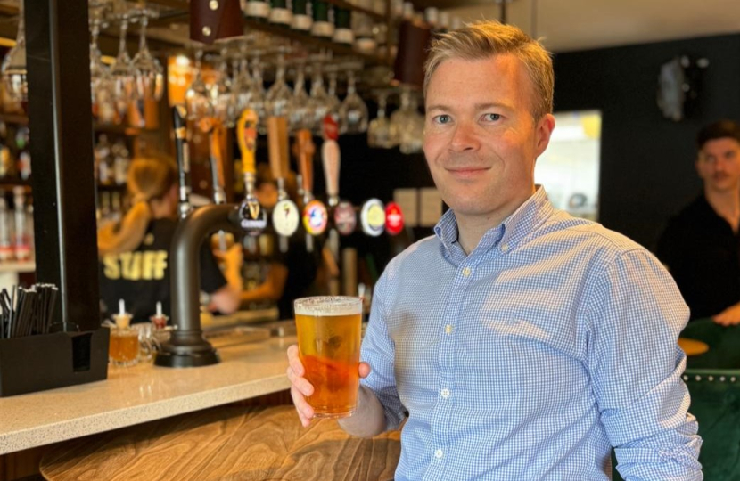 Bradley holding a pint at a bar